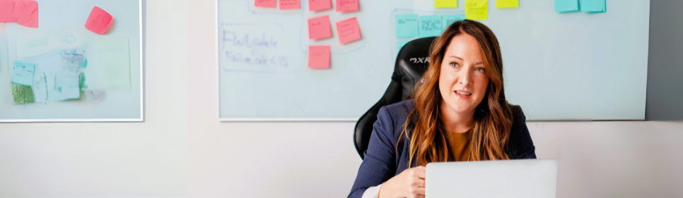 Woman with laptop in front of whiteboard