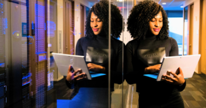 Woman by mirror holding laptop