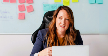 Woman with laptop in front of whiteboard