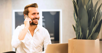 Guy on phone with laptop and plant